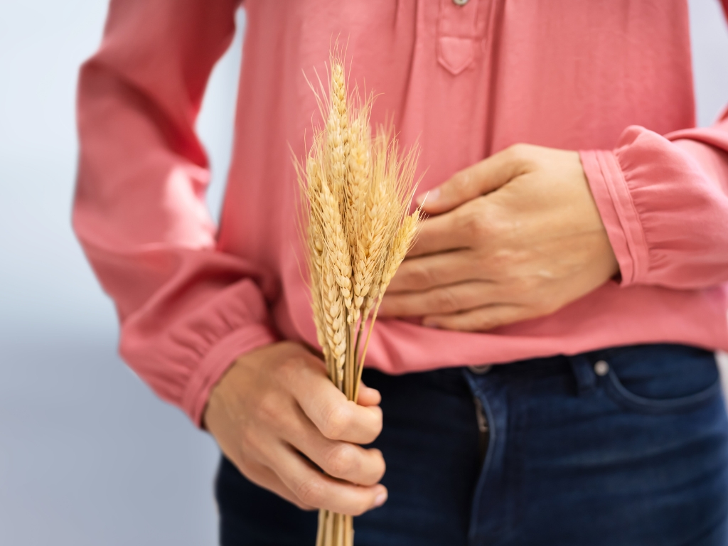 Symbolbild: Bauchbeschwerden durch Gluten – Frau mit Weizenähren als Hinweis auf Glutensensitivität.