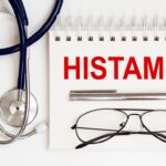 Stethoskop, Brille und Stift neben Notizblock mit dem Wort ‚Histamin‘ in roter Schrift – Symbolbild für Histaminintoleranz oder medizinische Diagnose.