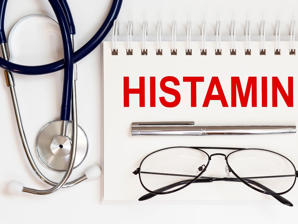 Stethoskop, Brille und Stift neben Notizblock mit dem Wort ‚Histamin‘ in roter Schrift – Symbolbild für Histaminintoleranz oder medizinische Diagnose.