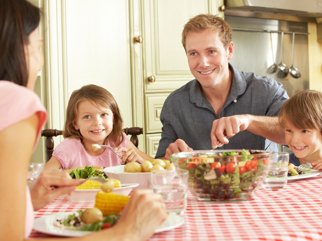Eine Familie isst zusammen am Esstisch und alle genießen ihr Essen. Auch die Person mit Nahrungsmittelunverträglichkeiten genießt ihr Essen. Ein Symbolbild für Gleichheit und Zusammenhalt.
