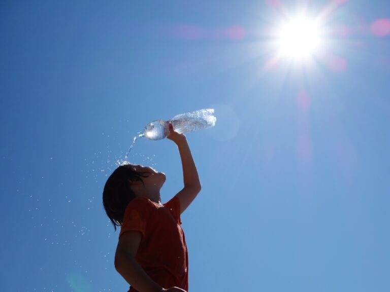 Junge kühlt sich mit Wasser in der prallen Sonne ab. Ein Sinnbild dafür, dass auch Menschen mit Intoleranzen die Hitze gut überstehen.