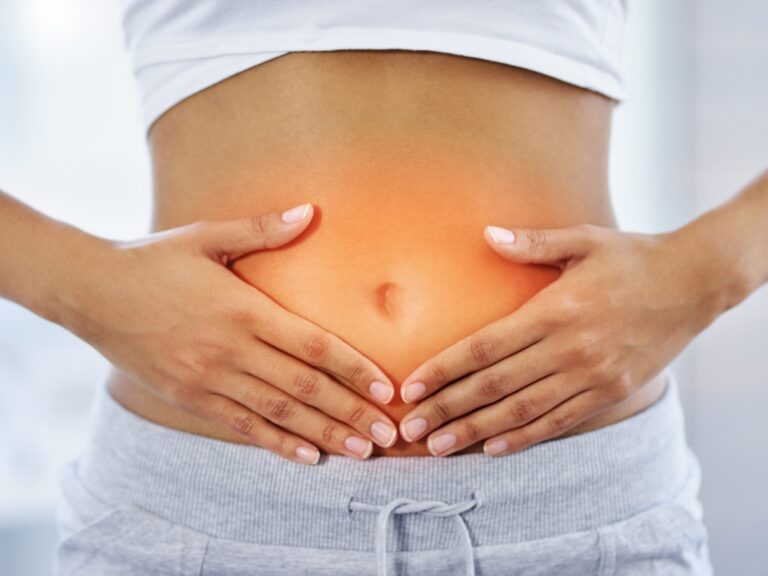 Auf dem Bild sieht man eine Frau die sich ihren Darm hält, als Anzeichen, dass sie einen Leaky gut haben könnte.