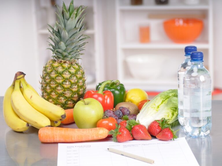 Im Bild sind ein paar Obst und Gemüsesorten zu erkennen und davor liegt ein Ernährungstagebuch. Dies soll Menschen mit Unverträglichkeiten helfen, ihre Symptomatik besser zu verstehen.