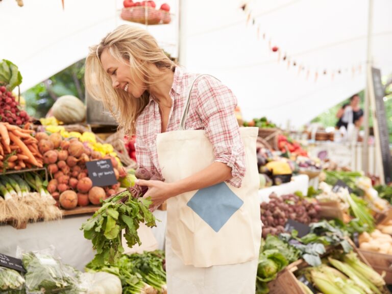 Eine Frau geht auf einem Markt einkaufen. Sie kauft trotz ihrer Unverträglichkeiten gut vorbereitet ein.